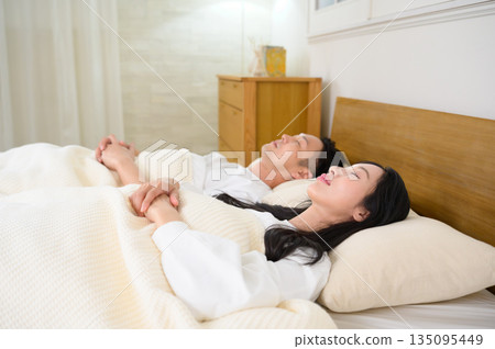 A man and a woman sleeping side by side in bed in a bedroom A man and a woman sleeping side by side in bed in a bedroom 135095449