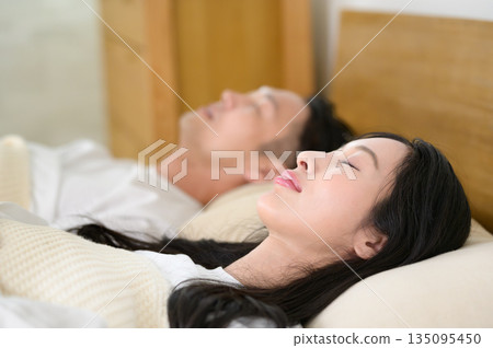 A man and a woman sleeping side by side in bed in a bedroom 135095450