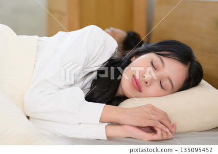 A man and a woman sleeping side by side in bed in a bedroom 135095452