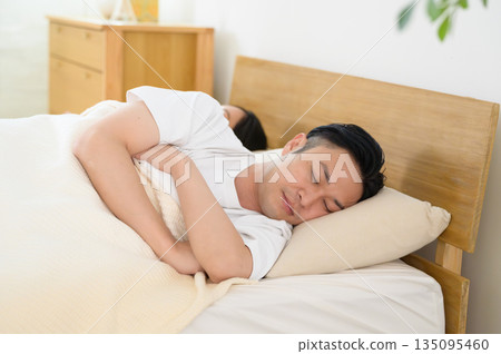 A man and a woman sleeping side by side in bed in a bedroom 135095460
