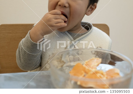Baby eating mandarin oranges with his hands 135095503