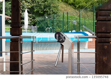 Entrance turnstile gate at swimming pool area on a sunny day. 135095748