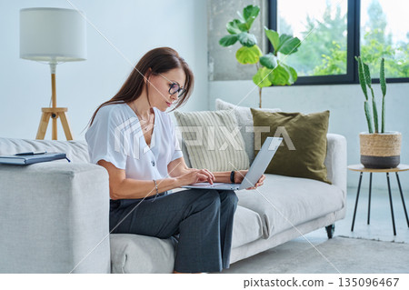 Middle aged serious woman working with laptop 135096467