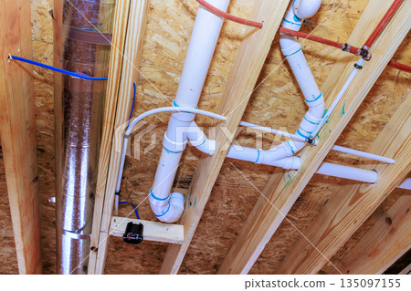 Pipes and ducts installed in ceiling of construction site plumbing and HVAC systems in progress Pipes and ducts installed in ceiling of construction site plumbing and HVAC systems in progress 135097155