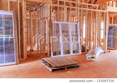 Construction site features walls, windows, wood in an unfinished interior 135097156