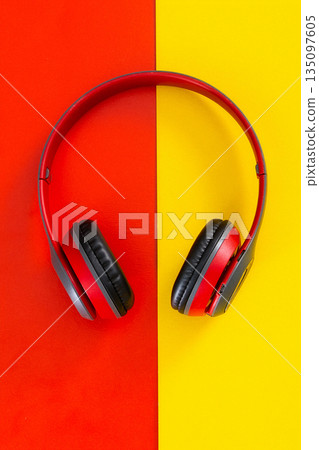 Red headphones on vibrant contrasting red yellow background 135097605