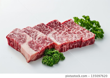 Aesthetically Arranged Premium Marbled Beef Cuts Garnished with Fresh Herbs on a White Background for a Culinary Delight 135097620