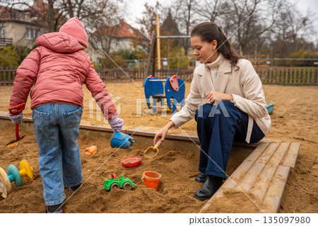 Child Explores With Vibrant Toys, Young Child Digs In Bright Sandbox Area, Kids Enjoying Imaginative Play With Colorful Tools Outdoors 135097980