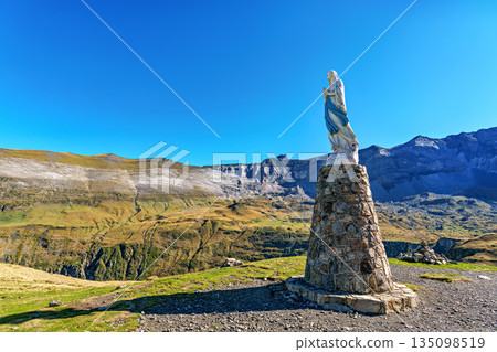 Blessed virgin Mary statue at Cirque de Troumouse, Heas in France. Meadows surrounded by dramatic mountain peaks 135098519