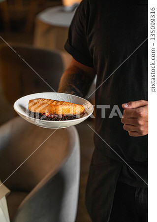 Grilled salmon fillet served by chef on plate Grilled salmon fillet served by chef on plate 135099316