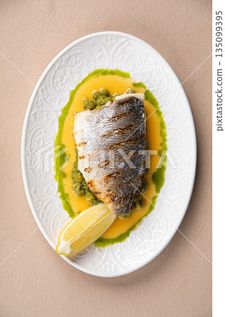 Pan seared sea bass with green pea puree 135099395