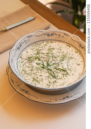 Cold okroshka soup with herbs served in bowl 135099406