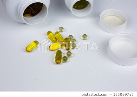 Softgel capsules with Omega 3 and vitamin D3 plus K2. Set of essential vitamins on white background for adding to food. Dietary supplements in capsules poured from jar 135099755