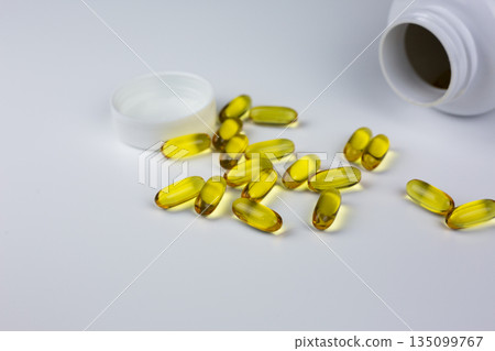 Soft gels pills with Omega-3 oil spilling out of pill bottle close-up. Gel capsules and jar. Omega 3, multivitamins, Calcium and antibiotics. Health and Immunity concept with dietary supplements 135099767