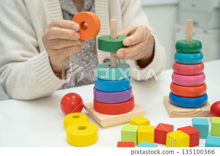 Asian elderly woman playing enhancing skill board game. Asian elderly woman playing enhancing skill board game. 135100366