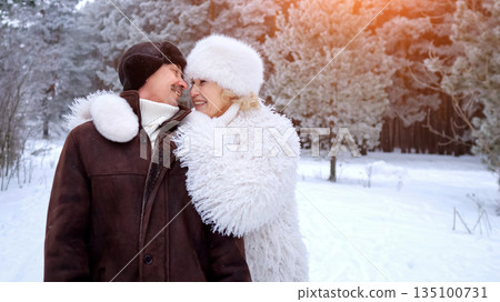 Models Exchanging Gentle Caresses Amidst Winter Forest, Tender Couple Embraces Under Snowy Pine Trees With Warm Lighting, Elegant Models In Furlined Attire Share Loving Kiss In Frosty Forest Glow Models Exchanging Gentle Caresses Amidst Winter Forest, Tender Couple Embraces Under Snowy Pine Trees With Warm Lighting, Elegant Models In Furlined Attire Share Loving Kiss In Frosty Forest Glow 135100731