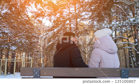 Sunset Glow Illuminates Peaceful Snowy Scene, Calm Winter Evening As Couple Gazes At Sunset Landscape, Serene Scene Of Lovers Seated On Bench Watching Sunset Through Pine Forest Canopy Sunset Glow Illuminates Peaceful Snowy Scene, Calm Winter Evening As Couple Gazes At Sunset Landscape, Serene Scene Of Lovers Seated On Bench Watching Sunset Through Pine Forest Canopy 135100807