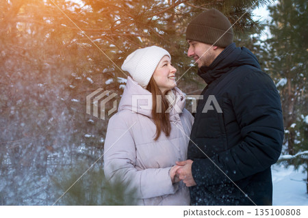 Smiling Pair Basking In Frosty Woodland Atmosphere, Happy Duo Relaxing Among Snowcovered Trees In Winter Landscape, Delighted Couple Enjoying Sunny Moments In Snowladen Forest During Winter Season Smiling Pair Basking In Frosty Woodland Atmosphere, Happy Duo Relaxing Among Snowcovered Trees In Winter Landscape, Delighted Couple Enjoying Sunny Moments In Snowladen Forest During Winter Season 135100808
