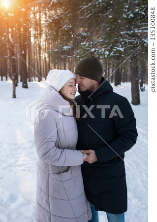 Lovers Sharing Warm Feelings Amidst Snowy Woods, An Affectionate Pair Exchanging Heat Beneath Icy Woodland Canopy, Two Individuals Found Comfort Together Within Cold And Snowy Forest Landscape 135100848