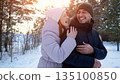 Laughter Shared During Cold Outdoor Adventure, Pair Chuckling Amidst Snowcovered Trees During Festive Season, Enthusiastic Duo Enjoying Frosty Walk Through Pine Forest With Cheerful Expressions 135100850