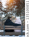Couple Rests Warmly, Winter Embrace With Peaceful Closeness, Snowy Scene Featuring Affectionate Partners Resting Peacefully, Two Individuals Sitting Intimately On Snowy Bench Amidst Pine Trees 135100851