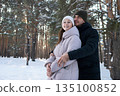 Couple Sharing Loving Winter Kiss, Two Affectionately Embracing Individuals In Cold Winter Forest Setting, Romantic Partners Sharing Gentle Kiss Amid Snowcovered Trees And Bright Sunlight 135100852