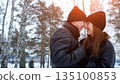 Romantic Couple Under Snowy Trees, Couple Sharing Warmth During Snowfall Beneath Winterly Pine Forest, Intimate Moment Between Lovers Surrounded By Snowcovered Trees And Gentle Winter Light 135100853
