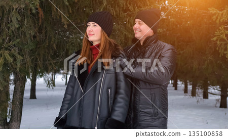 Couple In Winter Coats Looking Up, Man Hugging Woman Under Evergreen Trees With Warm Sunlight Flare, Beanies And Leather Jackets, Cozy Atmosphere, Candid Weekend Escape And Genuine Connection Couple In Winter Coats Looking Up, Man Hugging Woman Under Evergreen Trees With Warm Sunlight Flare, Beanies And Leather Jackets, Cozy Atmosphere, Candid Weekend Escape And Genuine Connection 135100858