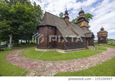Traditional wooden church with bell tower and stone path covered in flower petals 135100947