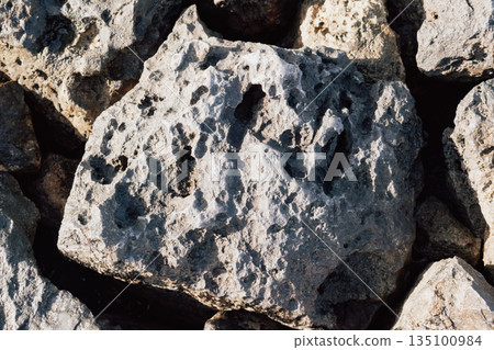 Dry ancient limestone rocks texture background pattern under harsh summer sunlight and shadows Dry ancient limestone rocks texture background pattern under harsh summer sunlight and shadows 135100984