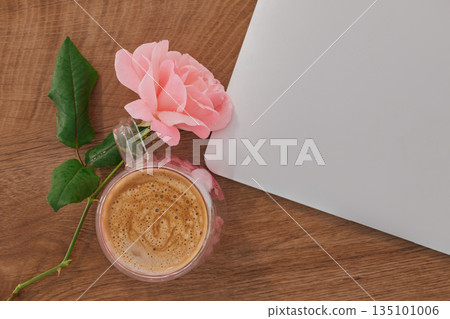 cozy home office aesthetic: pink rose and coffee mug next to a closed laptop on wooden desk cozy home office aesthetic: pink rose and coffee mug next to a closed laptop on wooden desk 135101006