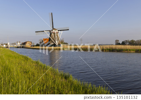 Dutch windmill by canal in Heerhugowaard, Netherlands Dutch windmill by canal in Heerhugowaard, Netherlands 135101132