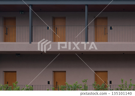 minimalist modern hotel facade: two stories of identical wooden doors and balconies 135101140