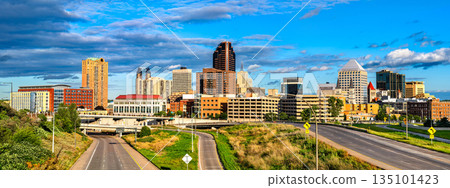 Saint Paul skyline stands in Minnesota, USA. Cityscape view features downtown skyscrapers and highway roads under a blue sky with clouds in the Twin Cities Saint Paul skyline stands in Minnesota, USA. Cityscape view features downtown skyscrapers and highway roads under a blue sky with clouds in the Twin Cities 135101423