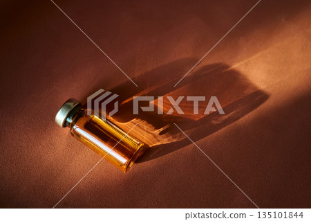 Vial containing amber liquid casting reflections on surface 135101844