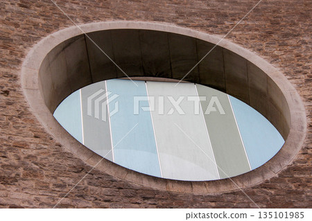 Oxford, United Kingdom - Dec 22, 2025: The Westgate Centre is a major shopping centre in Oxford. Beautiful round window made of pieces of glass of different colors against a brick wall. 135101985
