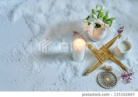 Imbolc altar celebrating brigid with cross, candle, snowdrops 135102607