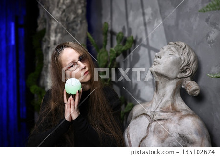 Enigmatic woman performs solemn offering near weathered sculpture 135102674