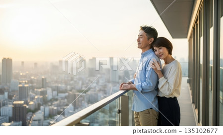 A couple watching the evening view of the city from the balcony of a tower apartment 135102677