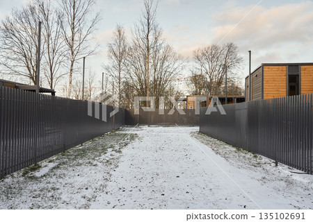 Pathway covered with snow leading to modern prefabs in quiet neighborhood 135102691