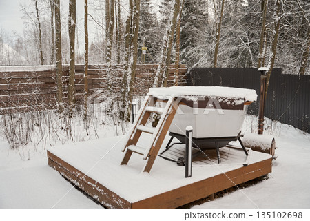 Frozen outdoor spa area surrounded by leafless trees and wintry sky Frozen outdoor spa area surrounded by leafless trees and wintry sky 135102698