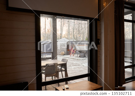 Serene snowy yard seen through warm indoor outdoor setting 135102711