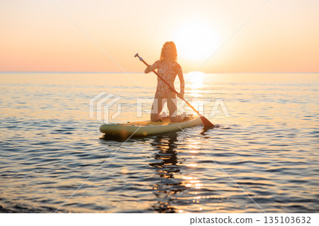 Young woman walking on stand up paddle sup boards by the sea during summer vacation 135103632