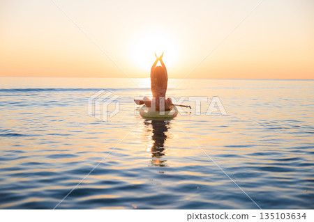 Young woman walking on stand up paddle sup boards by the sea during summer vacation 135103634