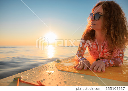 Young woman walking on stand up paddle sup boards by the sea during summer vacation 135103637