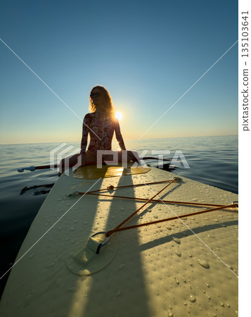 Young woman walking on stand up paddle sup boards by the sea during summer vacation 135103641
