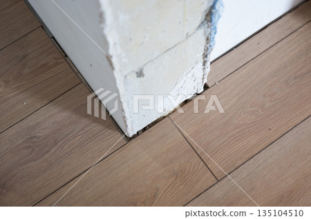 Laying laminate flooring around a concrete column during renovation 135104510