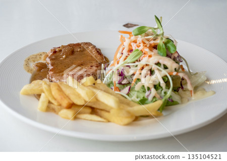 Close up of Grilled pork steak, boiled french fries and vegetable salad;Selective focus Close up of Grilled pork steak, boiled french fries and vegetable salad;Selective focus 135104521