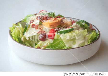 Caesar Salad: Crisp romaine lettuce tossed with Parmesan, croutons, and a creamy Caesar dressing, 135104526