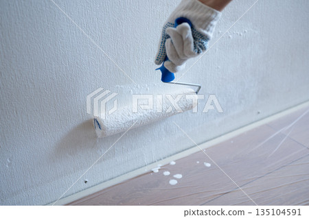 Painter using paint roller painting white wall Painter using paint roller painting white wall 135104591